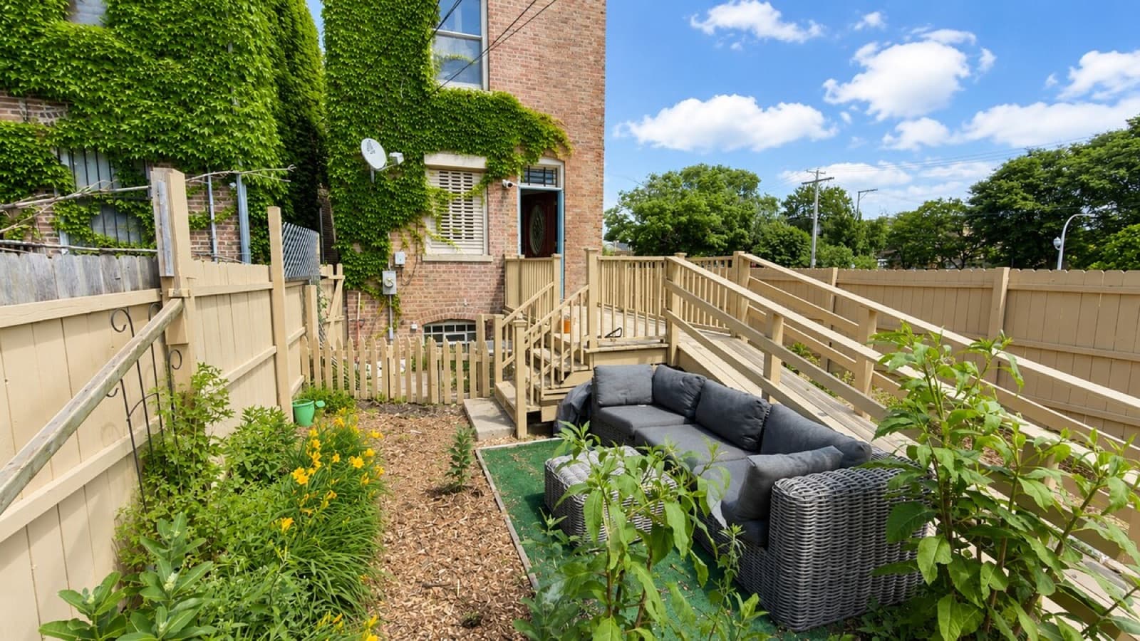 Rear yard with stained deck, privacy fence, and garden beds